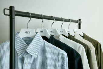 ブルーと白のストライプ、ネイビー、白、カーキ、ベージュのシャツがハンガーにかかっている