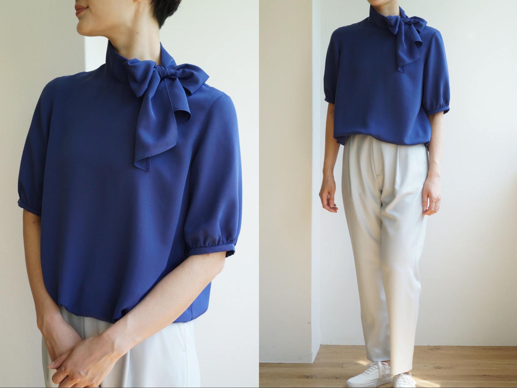 ネイビーのブラウスとホワイトのパンツを着用する女性