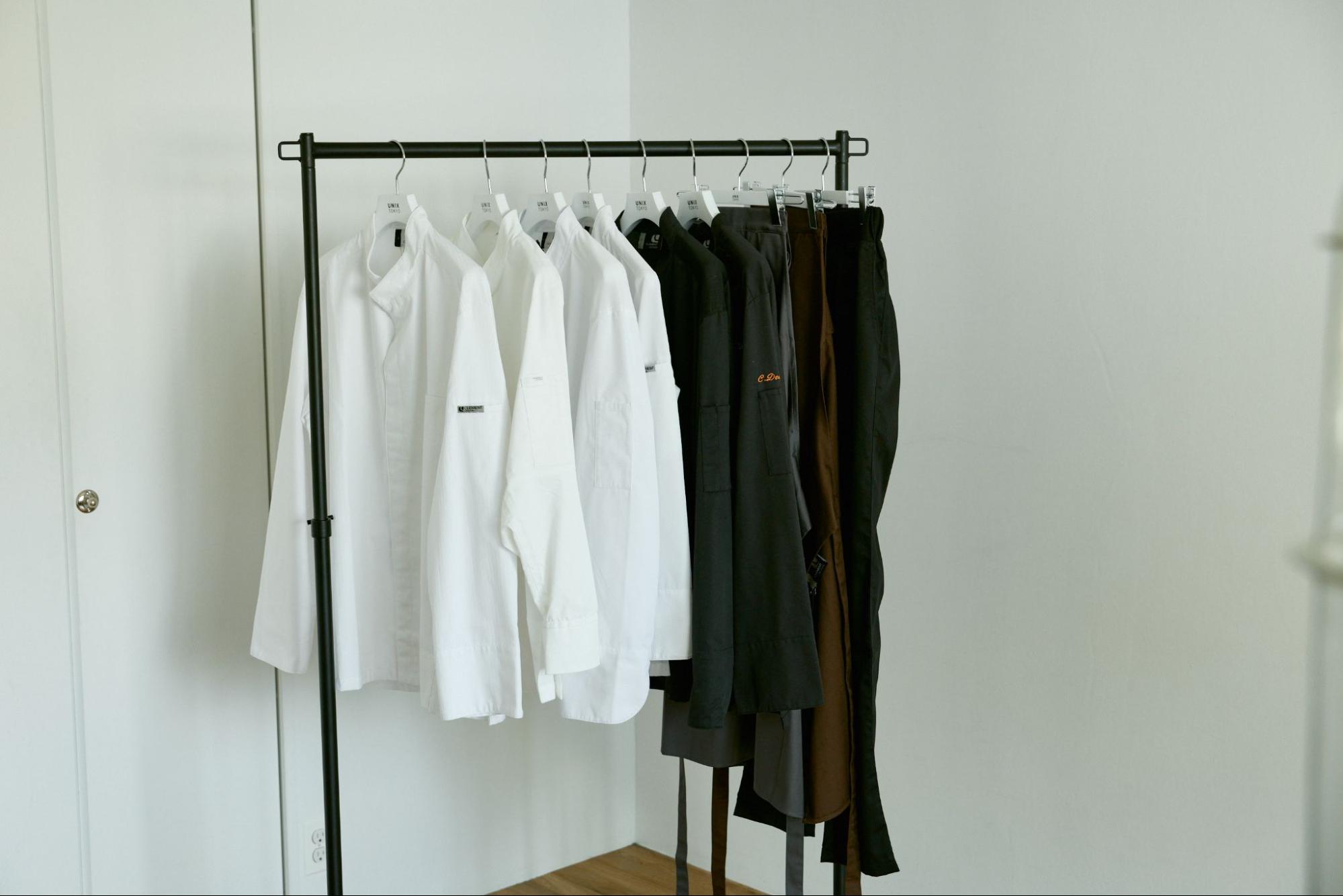 白いコックコートや黒いパンツがかけられているハンガーラック
